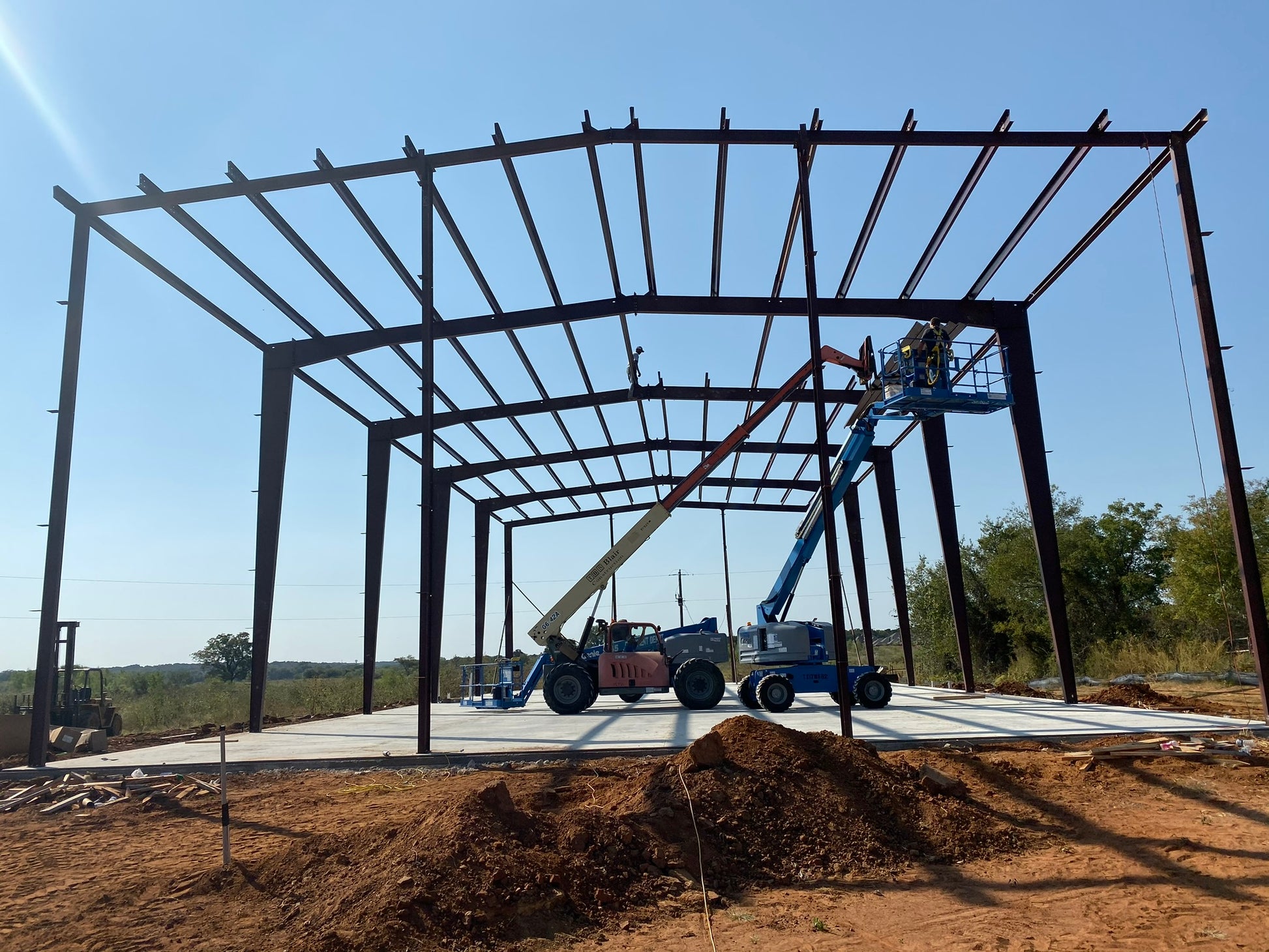Construction site with a large metal framework under construction against a blue sky.