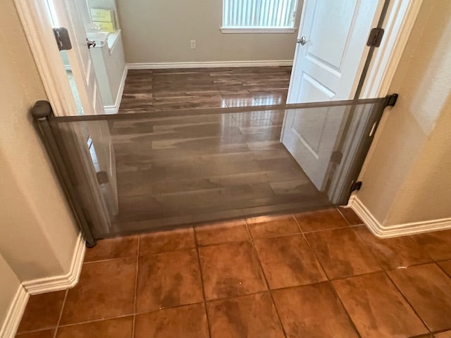 retractable pet gate installed across double door interior passageway with tiled floor