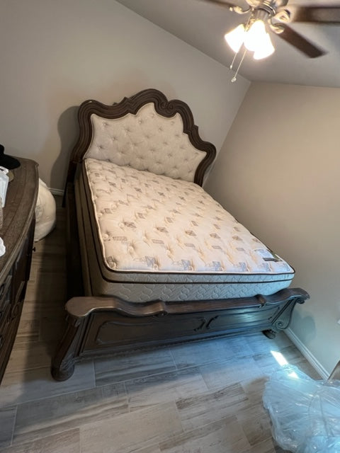 Wooden bed with tufted headboard in a room with a ceiling fan and light.